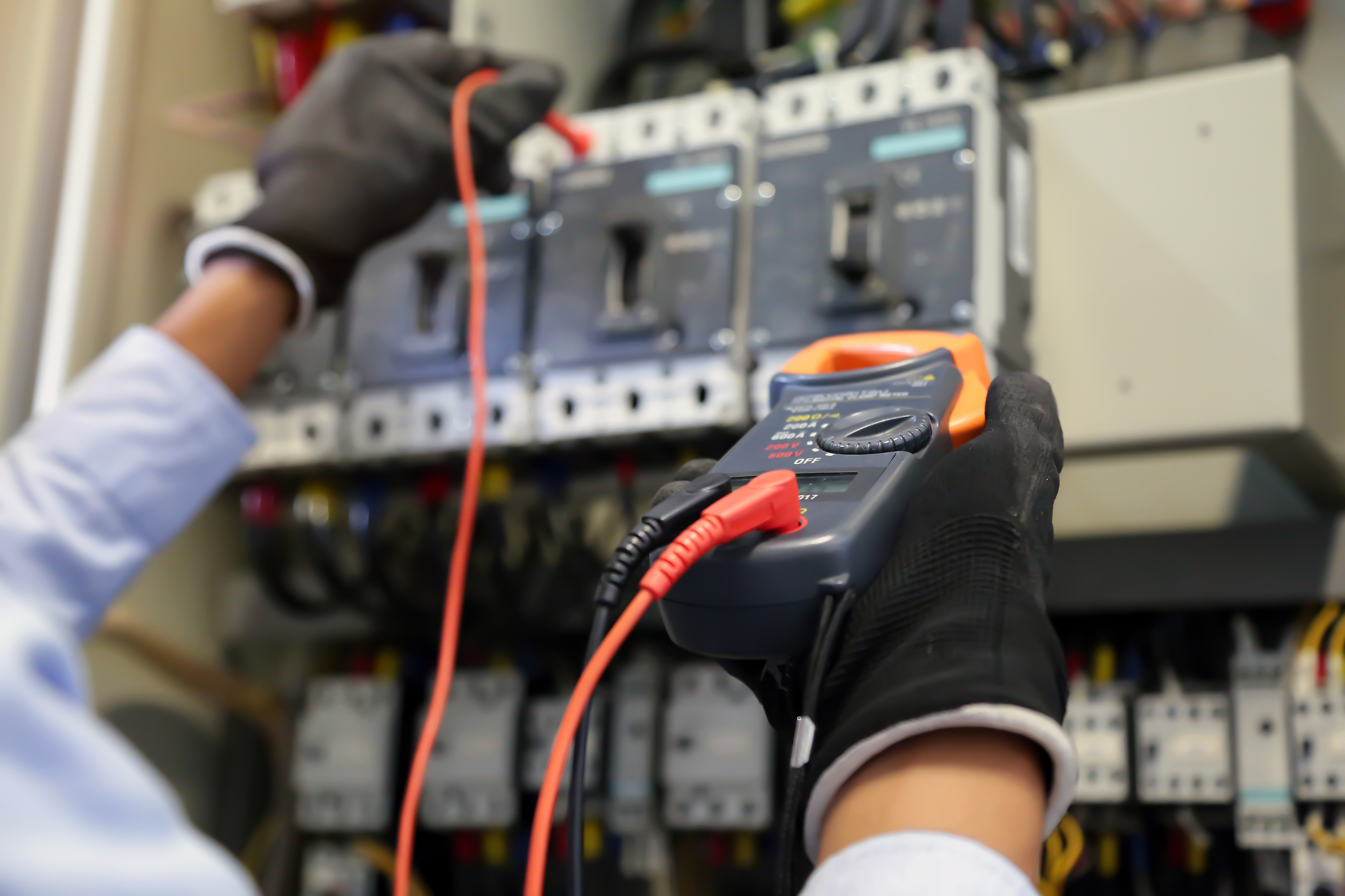 Electrical engineer using measuring equipment to checking electric current voltage at circuit breaker and cable wiring system for maintenance in main power distribution board.
